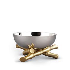 a white and gold bowl with two golden bones on it's legs, in front of a white background