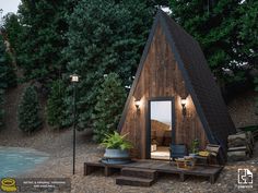 a small wooden cabin sitting on top of a gravel field next to a pool and trees