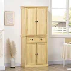 a tall wooden cabinet sitting next to a window in a room with wood floors and white walls