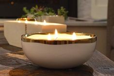 two white candles sitting on top of a wooden table next to each other in front of a fireplace