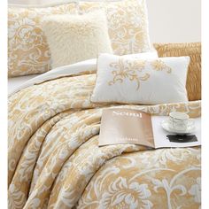 a bed covered in yellow and white comforters with pillows on top of it next to a pillow case