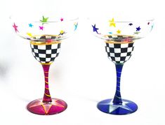 two wine glasses decorated with colorful designs and stars on the bottom one has a gold rim