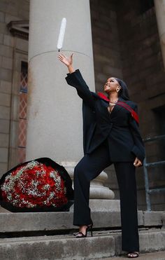 a woman in a black suit and red stoler is holding up a white umbrella