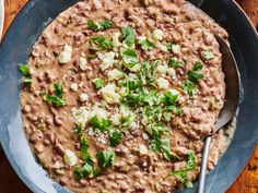 a bowl filled with beans and parsley on top of a wooden table