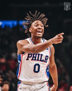 a basketball player with dreadlocks on his head pointing to the side while standing in front of an audience