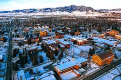 an aerial view of a city with mountains in the background and snow on the ground