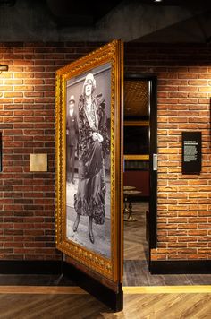 a brick wall with pictures on it in an old fashion museum display case and wooden flooring