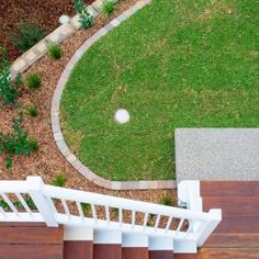 an overhead view of a wooden deck with white railings and steps leading up to a green lawn