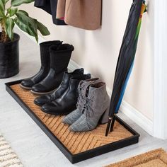 several pairs of boots and an umbrella on a mat