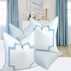 two blue and white pillows sitting on top of a bed in front of a window