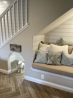 a dog is standing next to a couch in a room with wood floors and stairs