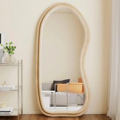 a large mirror sitting on top of a wooden floor next to a white shelf filled with books