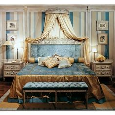 a bedroom with blue and white striped walls, gold bedding, and an upholstered canopy