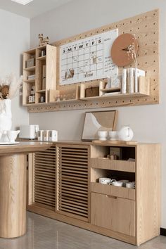 a wooden desk topped with lots of drawers next to a wall mounted calendar on the wall