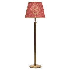 a lamp that is on top of a stand with a red lampshade over it