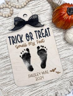 a wooden tag with the words trick or treat smell my feet on it next to pumpkins