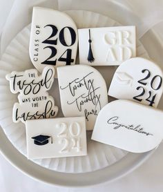 graduation cookies decorated with black and white icing are on a plate in the shape of graduation caps