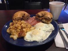 a blue plate topped with breakfast foods next to a cup of coffee on a table