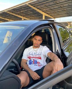 a man sitting in the driver's seat of a car with his legs crossed