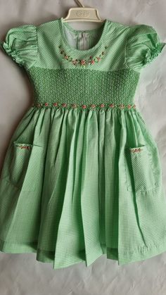 "This dress is smocked with matching green color and beautiful hand embroidered roses added around the neckline and on the smocking. The skirt comes with matching pockets, with same detailed hand embroidered roses.   Dress is fully lined with matching soft cotton material. The back closes with a zip and tie sashes. Material Outer fabric - Polycotton Inner fabric -100% Cotton  Instructions Cold gentle hand wash Available sizes, Size 3-6 months (AU 00) Length 14\" Chest circumference 20\" Size 6-12 months (AU 0) Length 16\" Chest circumference 21\" Size 1  (12-18 months) Length 18\" Chest circumference 22\" Size 2 (18-24 months) Length 20\" Chest circumference 23\" Size 3 Length 22\"  Chest circumference 24\" Size 4  Length 24\"  Chest circumference 25\" Size 5   Length 26\"  Chest circumfer Gingham Dress With Smocked Bodice For Garden Party, Cute Fitted Dress With Smocked Cuffs, Gingham Dress With Smocked Back For Garden Party, Short Sleeve Gingham Smock Dress, Gingham Short Sleeve Dress With Smocked Bodice, Short Sleeve Gingham Dress With Smocked Bodice, Gingham Dress With Smocked Bodice And Short Sleeves, Green Cotton Smocked Dress For Spring, Green Cotton Smocked Summer Dress