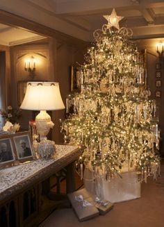 a white christmas tree in a living room next to a table with presents on it