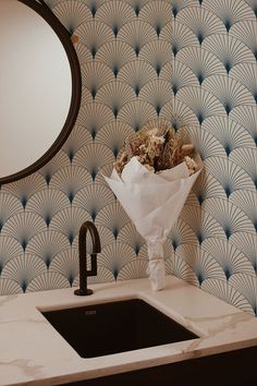 a bouquet of flowers sitting on top of a counter next to a sink and mirror