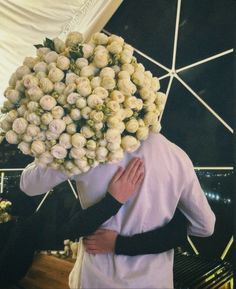 a man holding a bunch of flowers over his face