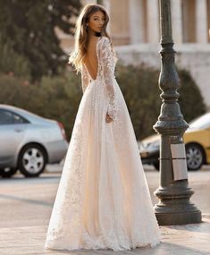 a woman in a wedding dress standing next to a street light with her back turned