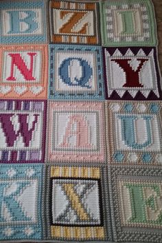 a crocheted blanket with letters and numbers in squares on the bottom, one letter is