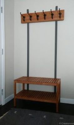 a wooden bench sitting in front of a wall mounted coat rack with hooks on it