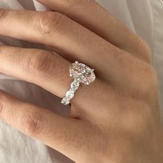 a woman's hand with a diamond ring on top of her finger and the other hand holding an engagement ring