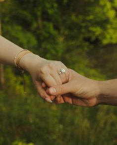 two people holding hands with trees in the background