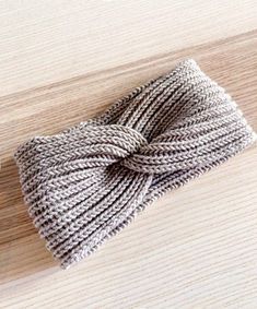 a close up of a knitted headband on a wooden surface with one knot