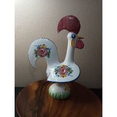 a ceramic rooster figurine sitting on top of a wooden table next to a wall