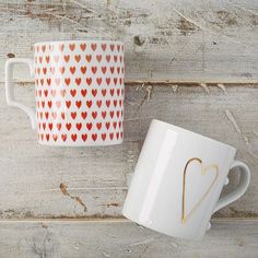 two coffee mugs with hearts painted on them