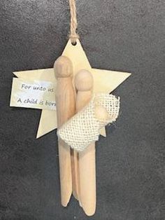 two wooden pegs are hanging from a star ornament that says for unto us as child is born