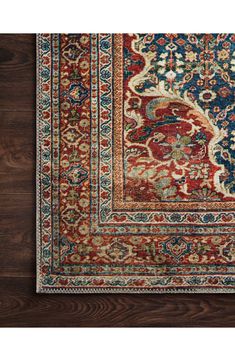 an antique persian rug with red, blue and green colors on wood flooring area