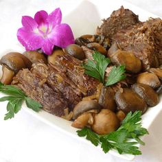 meat, mushrooms and parsley on a plate with a purple flower in the background