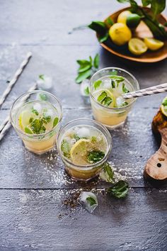 three glasses filled with lemonade, mint and lime juice on a table next to a bowl of lemons