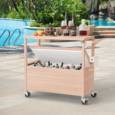 an outdoor bar cart filled with bottles and drinks next to a swimming pool in the background