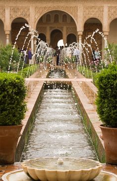 a fountain in the middle of a courtyard with potted plants