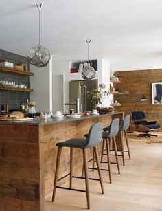 a kitchen with wooden flooring and counter top next to bar stools in front of it