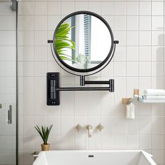 a white bath tub sitting next to a bathroom sink under a round mirror on the wall