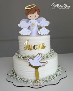 a three tiered cake decorated with an angel and the word lucas on it's side