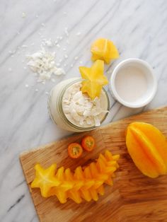 sliced mangoes and other fruits on a cutting board next to a jar of yogurt