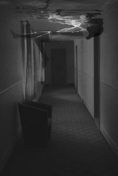 an empty hallway is shown in this black and white photo, with curtains hanging from the ceiling