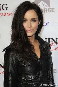 a woman with long hair wearing a black leather jacket and posing for the camera on a red carpet