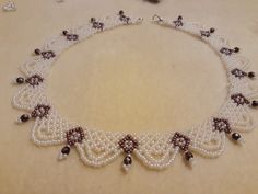 a white necklace with pearls and black beads on a beige tablecloth next to other jewelry items