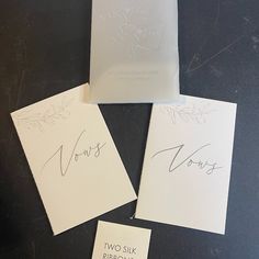 three cards with writing on them sitting on a table next to two envelopes that say vows and two silk ribbons