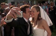 a bride and groom taking a selfie in front of their guests at a wedding